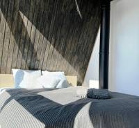 A bed with a striped blanket and wooden walls in a cabin.