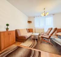 Living area of a studio apartment with brown furniture and a wooden decor floor.