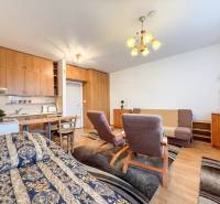 Studio apartment with a bed, kitchenette, and wood-patterned flooring.