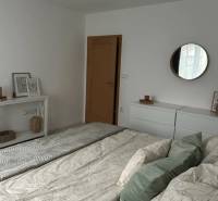 Bedroom in a 2-room apartment with white furniture and a bed with pillows.