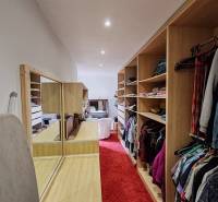 A wardrobe in a family house with a red carpet and built-in shelves.