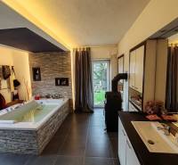 Spacious bathroom with a bathtub and tiles in a family house, floor with wood decor.