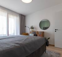 A bedroom with a bed, mirror, and dresser, on a floor with a wooden decor in a 2-room apartment.