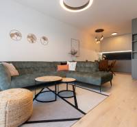 Living room in a two-room apartment with a sofa, coffee tables, and wood-patterned flooring.