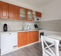 A kitchen in a 2-room apartment with wooden cabinets, a dishwasher, and a dining table.