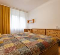 A bedroom in a two-room apartment with yellow curtains and wooden furniture.