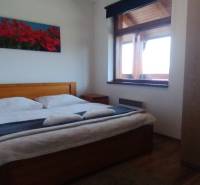 Bedroom with a double bed, a picture of flowers, and a wardrobe in a two-room apartment.