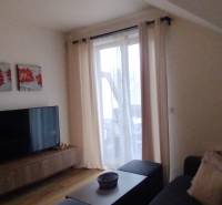 Living room in a two-room apartment with a wooden decor floor, decoration, and a television.