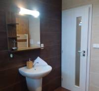 Bathroom in a 2-room apartment with a sink, mirror, and light tiles.