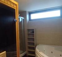 A bathroom with a bathtub, shower, sauna, and window in a 2-room apartment.