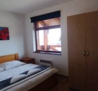 Bedroom with a double bed, wooden decor flooring, and a wardrobe in a 2-room apartment.