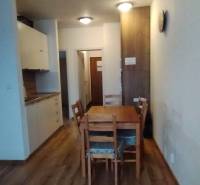 Dining room in a 2-room apartment with a wooden decor floor and a wooden table.