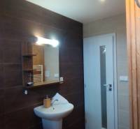 Bathroom in a 2-room apartment with dark tiles, a mirror, and a white washbasin cabinet.