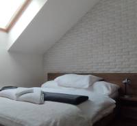 A bedroom in a 2-room apartment with a bed, a skylight, and a brick cladding.