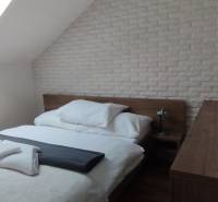 Bedroom with a bed and a skylight in a 2-room apartment with decorative brick cladding.
