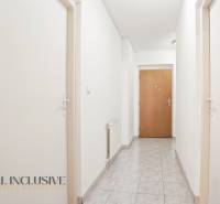 A corridor with white walls, tiles, and wooden doors in a 2-room apartment.