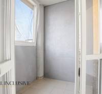 Glazed balcony wall in a 2-room apartment with simple tiles and gray walls.
