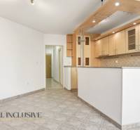A kitchen in a 2-room apartment with white walls and tiled flooring.