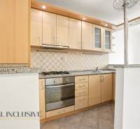A kitchen in a 2-room apartment with wooden cabinets and a stone countertop.
