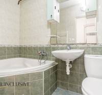 A bathroom in a 2-room apartment with a bathtub, sink, and toilet, tiled with green tiles.