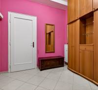 A hallway in a 3-room apartment with pink walls, white doors, and a wardrobe.