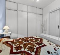 A bedroom with a decorative quilted bedspread in a 3-room apartment with minimalist furnishings.