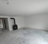 Interior of a family house with a fireplace and staircase, awaiting completion.