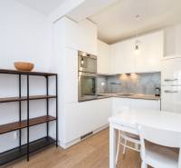 A kitchen in a 2-room apartment with white cabinets, a dining table, and a wooden decor floor.