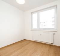 A room in a 2-room apartment with a wooden decor floor and a window with a radiator.