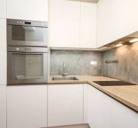 A kitchen in a 2-room apartment with built-in appliances and a kitchen unit with a wooden decor.
