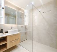 Bathroom in a 2-room apartment with a large mirror and a glass shower enclosure.