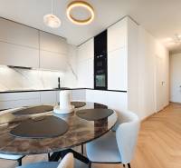 Dining area with a marble table and kitchen in a 2-room apartment, floor with wood decor.
