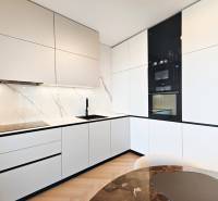A kitchen in a 2-room apartment with white cabinets and a wood-patterned floor.