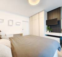 Bedroom in a 2-room apartment with a bed, wardrobe, and a TV on the wall.