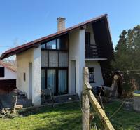 A cottage in Zlaté Moravce with a wooden fence, lawn, and trees around.