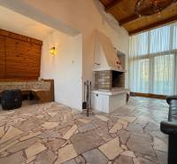 Interior of a cabin with a fireplace and seating, stone floor.