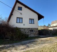 A cottage in Zlaté Moravce with a stone foundation and a sloped roof under a blue sky.