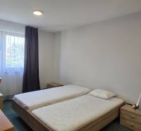 A bedroom with two beds, a desk, and a window in a three-room apartment.