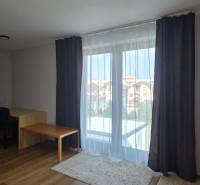 Living room with a table and wood-patterned flooring in a 3-room apartment.