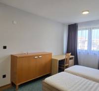 A bedroom with beds and furniture in a 3-room apartment, white walls, floor with wooden decor.