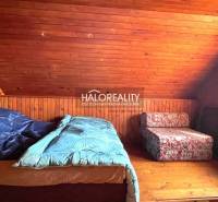 Attic room in a cottage with wooden paneling and two beds.