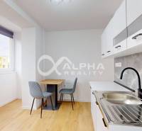 A kitchen in a studio apartment with a wood-patterned floor and a dining table.
