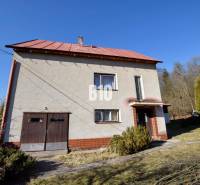 A family house in Raková with a garage, surrounded by a garden and trees.