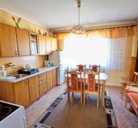 A kitchen unit with a wooden decor, a dining table, and chairs in a family house.