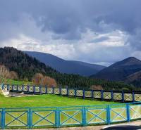 Mountain scenery in Donovaly with a blue wooden fence and forests in the background.