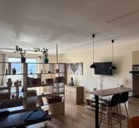 A living room in a one-room apartment with light furniture and a wooden decor floor.