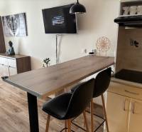 A dining counter in a studio apartment with a wood-patterned floor and modern furniture.