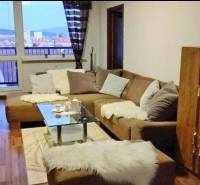 Living room in a three-room apartment with a sofa, glass table, and a view from the window.