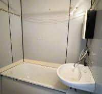Bathroom in a 3-room apartment with a bathtub, sink, simple tiles, and a bathroom cabinet.