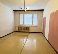 A room in a three-room apartment has a floor with a wood-effect decor and a radiator.